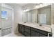 Bathroom with gray cabinets, double sinks, large mirror, and doorway to walk-in closet at 6690 Wake St, St Cloud, FL 34771