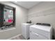 Functional laundry room with washer, dryer, utility sink, shelving, and modern finishes at 5933 Slate Rock Dr, Lakeland, FL 33811