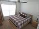 Cozy bedroom with a plaid bedspread, ceiling fan, and a large window providing ample natural light at 206 Samantha Ave, Auburndale, FL 33823
