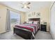 Comfortable bedroom with a dark wood frame bed, ceiling fan, and bright window view at 4422 Evergreen Forest Loop, Kissimmee, FL 34758