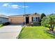 Charming single-story home with a manicured lawn, tan exterior, and attached two-car garage at 2612 Canyon Crest Dr, Lakeland, FL 33811
