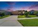 Single-story home with a manicured lawn, tan exterior, and attached two-car garage at dusk at 2612 Canyon Crest Dr, Lakeland, FL 33811