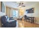Cozy living room featuring a plush leather sofa, ceiling fan, and a dedicated workspace at 9345 Se 171St Le Flore Ln, The Villages, FL 32162