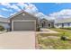 Charming gray home with a two-car garage, lush lawn, driveway, landscaped walkway, and inviting front entrance at 181 Osprey Heights Dr, Winter Haven, FL 33880