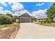 Charming gray home featuring a two-car garage, lush lawn, driveway, and quaint brick-lined landscaping at 181 Osprey Heights Dr, Winter Haven, FL 33880