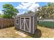 Gray and white storage shed in backyard with double doors and window at 181 Osprey Heights Dr, Winter Haven, FL 33880