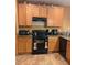 Traditional kitchen with granite countertops, wood cabinets, and modern black appliances at 1895 Snapper Dr, Kissimmee, FL 34759