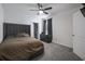 Carpeted bedroom features queen-sized bed, gray headboard, dark curtains, and ceiling fan at 5189 Greenheart Ave, Mount Dora, FL 32757