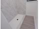 White tile shower with hexagon mosaic flooring and marble-patterned walls at 808 S Clara Ave, Deland, FL 32720