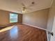 Bedroom with light brown walls, hardwood floors, ceiling fan, and a window overlooking the backyard at 4300 Meadow Ridge Ave, Mulberry, FL 33860