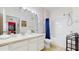 Bright bathroom featuring double sinks, a large mirror, shower and bath with blue curtain at 7654 Comrow St # 202, Kissimmee, FL 34747