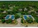 Aerial view of the community tennis courts, a basketball court and parking area surrounded by trees at 24 Lake Vista Way, Ormond Beach, FL 32174