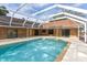 Backyard pool with a screened enclosure, a concrete deck and access to the brick house at 24 Lake Vista Way, Ormond Beach, FL 32174