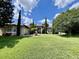 Beautiful home exterior with a well-maintained lawn, elegant landscaping, and blue skies with white clouds at 16325 Magnolia Bluff Dr, Montverde, FL 34756