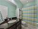 Stylish bathroom with a granite countertop vanity, toilet, shower and blue and green striped shower curtain at 3939 Sunset Lake Dr, Lakeland, FL 33810
