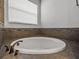 Close-up of a white tub surrounded by brown tiling and a faucet near a window with blinds at 3939 Sunset Lake Dr, Lakeland, FL 33810