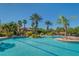 An expansive community pool features palm trees and blue umbrellas, providing a serene and resort-like atmosphere at 3939 Sunset Lake Dr, Lakeland, FL 33810