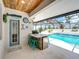 Outdoor patio featuring a built-in kitchen, travertine tile, and a wood plank ceiling, perfect for outdoor dining and entertaining at 3939 Sunset Lake Dr, Lakeland, FL 33810