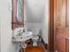 Compact, vintage bathroom with a unique pedestal sink, toilet, and a wood door at 485 E Stanford St, Bartow, FL 33830