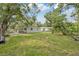 Expansive backyard features a lush lawn and a charming white house with a covered patio at 728 Trenton Rd, Lakeland, FL 33815