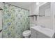 A modern bathroom offers gray vanity with sink, toilet, floral-patterned shower curtain, mirror, and shelves at 728 Trenton Rd, Lakeland, FL 33815