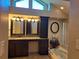 Bathroom featuring double sinks, granite counters, decorative mirrors, and a soaking tub at 12430 Blue Heron Way, Leesburg, FL 34788