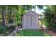 A storage shed surrounded by green grass, foliage, and a small swing at 12430 Blue Heron Way, Leesburg, FL 34788