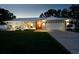 Charming single-story home with manicured lawn, stone accents, and well-lit driveway at dusk at 3610 Amber Ln, Lakeland, FL 33812