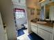 Bright bathroom features a vanity with double sinks, a large mirror, and blue accent rugs at 205 Golf Aire Blvd, Haines City, FL 33844