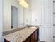 Elegant bathroom featuring a granite countertop, wood cabinets, and a large mirror at 2806 Spinning Silk Ct, Kissimmee, FL 34747