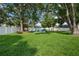 Well-maintained backyard featuring a white fence, lush lawn and mature shade trees at 811 Patricia Pl, Lakeland, FL 33809