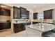 A view of a well-lit kitchen featuring granite countertops, stainless steel appliances, and dark wood cabinets at 1140 Terralago Way, Kissimmee, FL 34746