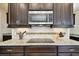 Close-up of stovetop and granite countertop with dark cabinets and mosaic backsplash adding a touch of elegance at 1140 Terralago Way, Kissimmee, FL 34746
