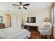 Cozy bedroom with hardwood floors, ceiling fan, sitting chair and a large TV at 1140 Terralago Way, Kissimmee, FL 34746