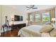 Stylish bedroom with hardwood floors, a ceiling fan, sitting chair and pool views at 1140 Terralago Way, Kissimmee, FL 34746