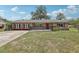 Charming brick home with a well-maintained lawn, red accents and black metal fence at 1212 Blake Ave, Auburndale, FL 33823