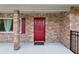 Inviting front porch featuring a striking red door and brick facade at 1212 Blake Ave, Auburndale, FL 33823