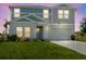 Two-story home with gray and blue siding, white trim, and a two-car garage, set on a green lawn at dusk at 1424 Axel Cir, Winter Haven, FL 33880