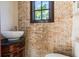 Quaint half-bath features a pedestal sink with a brick accent wall providing a rustic charm and warmth at 952 Moss Ln, Winter Park, FL 32789
