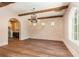Open dining room features brick accent wall, wood beams, hardwood floors, and modern lighting at 952 Moss Ln, Winter Park, FL 32789