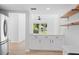 Modern white kitchen with stainless appliances, open shelving and hardwood flooring at 19795 Sw 85Th Loop, Dunnellon, FL 34432
