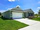 Green single-story home with a two-car garage, driveway, well-manicured lawn, and landscaped garden at 3148 Caspian Feather St, Bartow, FL 33830