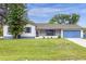 Charming single-story home with a blue garage door and shuttered windows, surrounded by a lush green lawn at 3331 Lime Tree Dr, Edgewater, FL 32141