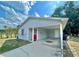 Charming single story home featuring a red front door, covered parking, and small front yard at 1310 Payne St, Auburndale, FL 33823