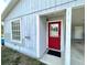 Close up of the home's entrance, showing a bright red door and covered carport area at 1310 Payne St, Auburndale, FL 33823