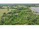 Aerial view showcases a tranquil landscape with verdant trees, open pastureland, and a glimpse of a pond at 1611 County Road 753S, Webster, FL 33597