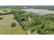 Expansive aerial shot showcases a home with outbuildings nestled amongst trees with a well-maintained lawn and lake nearby at 1611 County Road 753S, Webster, FL 33597