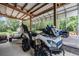 View of heavy-duty all terrain vehicles under the carport with the tractor in the background at 1611 County Road 753S, Webster, FL 33597