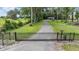 Long gravel driveway leading to a charming home, secured by an iron gate and picturesque trees at 1611 County Road 753S, Webster, FL 33597