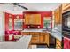 Red-themed kitchen with wooden cabinets, an island with cooktop, and a small dining area by the window at 1611 County Road 753S, Webster, FL 33597